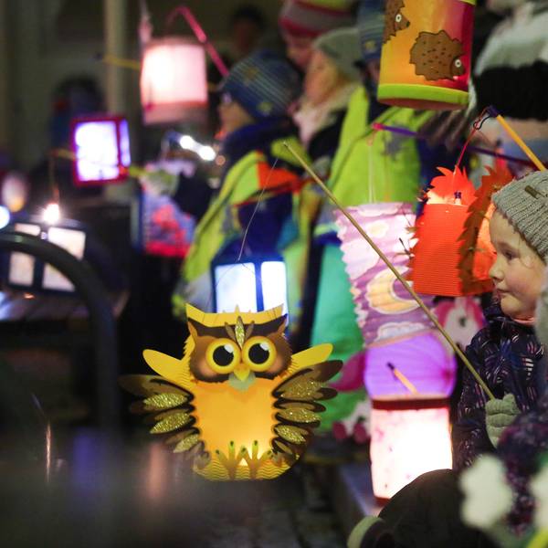 Kinder ziehen am mit ihren leuchtenden Laternen bei einem St. Martins-Umzug durch die Straßen.