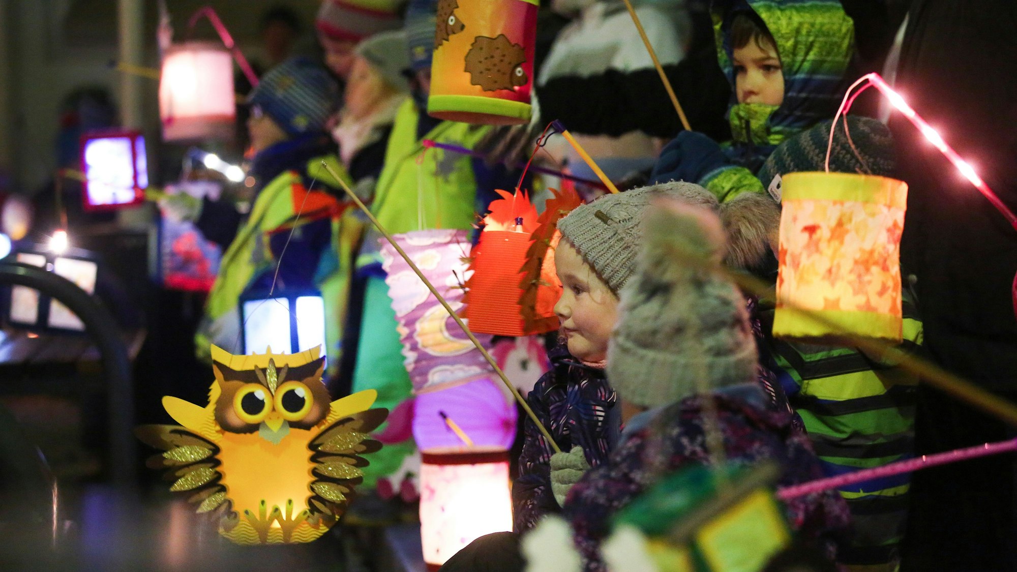 Kinder ziehen am mit ihren leuchtenden Laternen bei einem St. Martins-Umzug durch die Straßen.