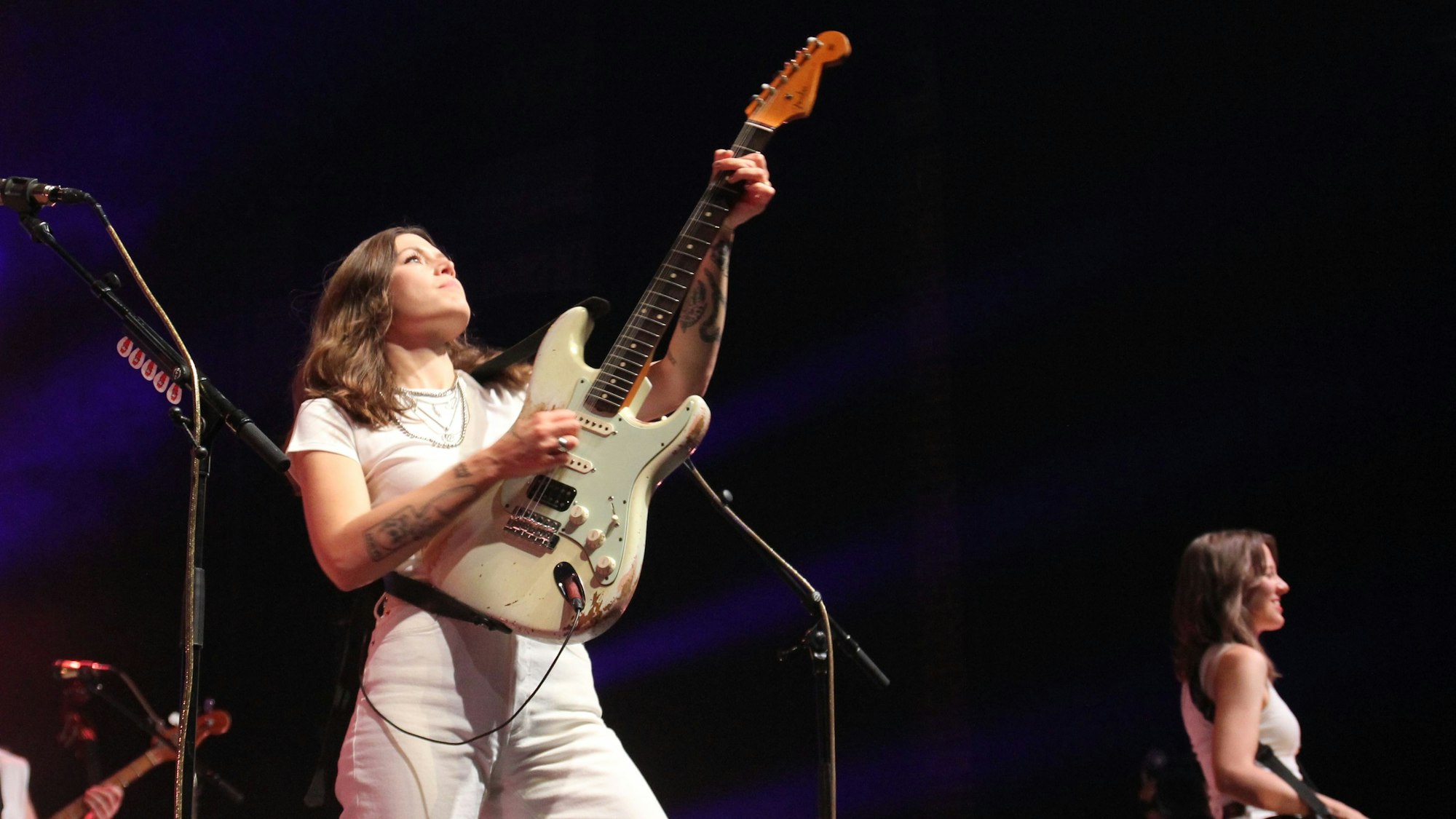 Rebecca Lovell hält ihre Gitarre in Rockstar-Manier beim Spiel in die Höhe.