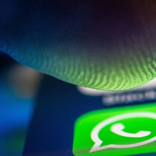 Ein Finger nähert sich dem Whatsapp-Logo auf einem Smartphone.