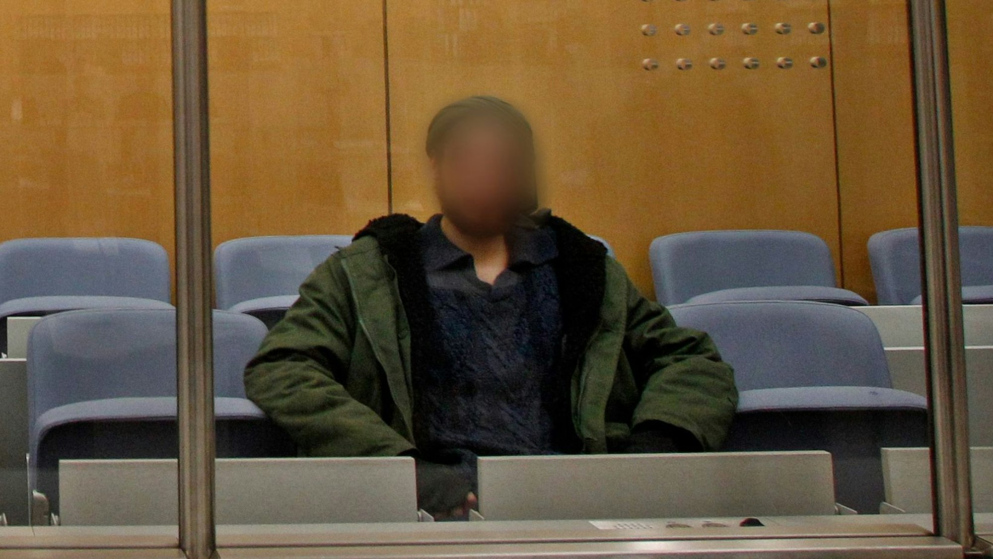 ARCHIV - 22.12.2016, Nordrhein-Westfalen, Düsseldorf: Der Angeklagte wartet hinter einer Sicherheitsscheibe vor dem Oberlandesgericht auf den Prozessbeginn. Er wurde am 6. April 2017 als IS-Terrorist vom Düsseldorfer Oberlandesgericht zu fünf Jahren Jugendhaft verurteilt. Gegen den am 24.10. in Duisburg festgenommenen vorbestraften Islamisten ist Haftbefehl erlassen worden, teilte die Generalstaatsanwaltschaft Düsseldorf am Mittwoch mit. Der 29-Jährige soll sich gegenüber einem Chatpartner in Syrien zur Begehung eines islamistisch motivierten Anschlags auf eine pro-israelische Demonstration bereiterklärt haben. Foto: picture alliance / Roland Weihrauch/dpa - ACHTUNG: Das Gesicht des Angeklagten wurde auf Verfügung des Gerichts gepixelt. +++ dpa-Bildfunk +++