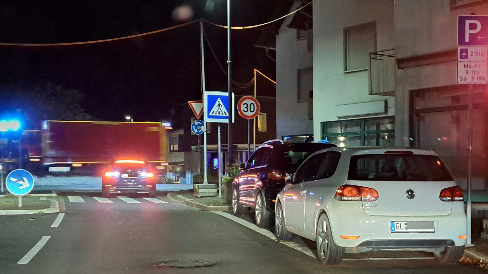 Mehrere Autos warten nachts an einer roten Baustellenampel, ein Einsatzfahrzeug der Feuerwehr fährt mit eingeschaltetem Blaulicht vorüber.