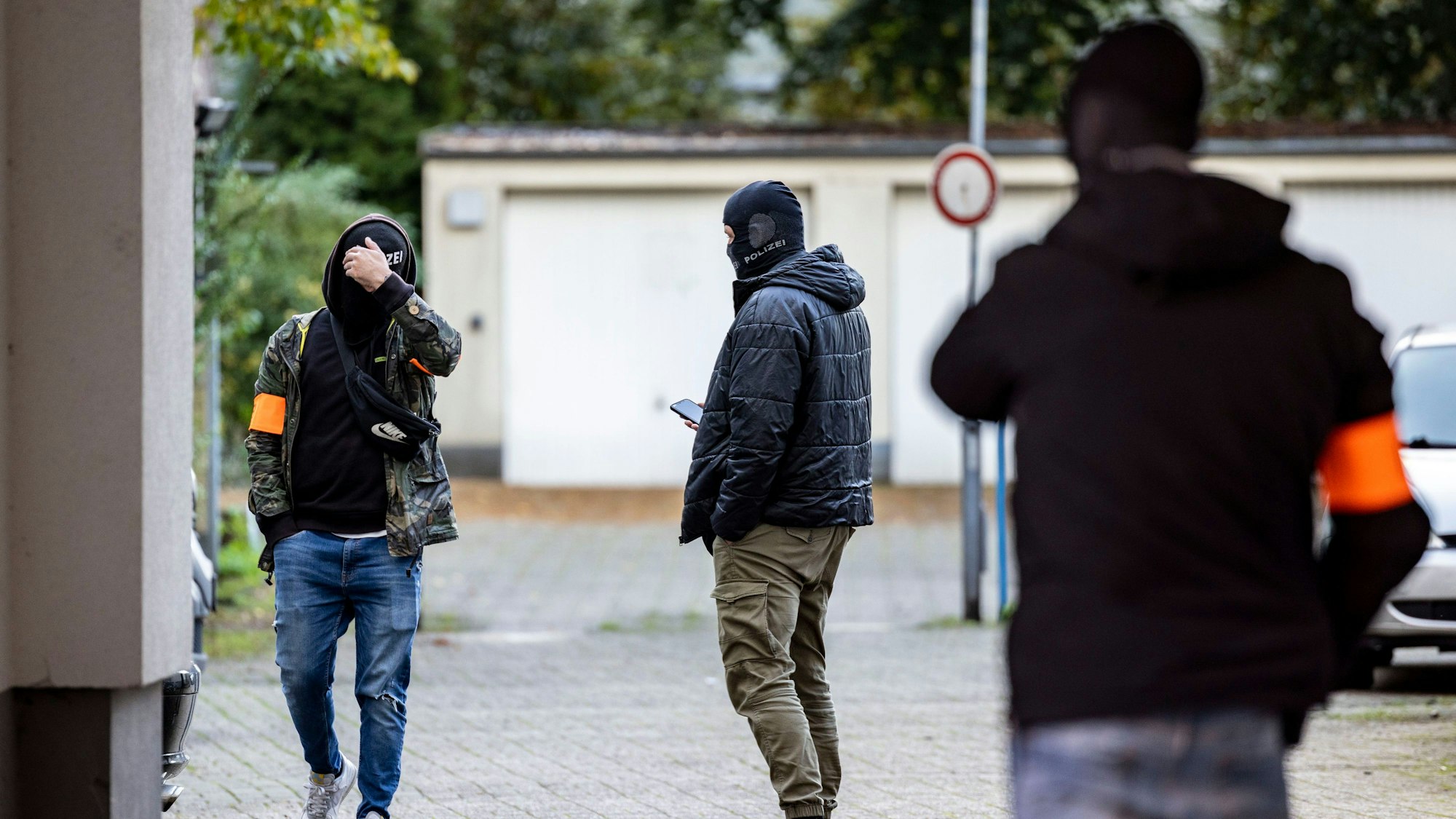 Drei Polizeibeamte stehen nach der Festnahme des Verdächtigen am Dienstagnachmittag auf dem Garagenhof des Hauses, in dem der Mann festgenommen wurde.