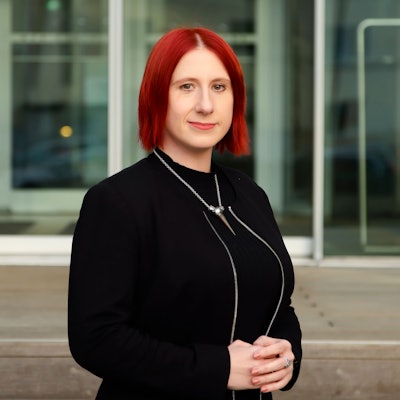 Lydia Benecke trägt ein schwarzes Kleid und eine schwarze Jacke und blickt in die Kamera