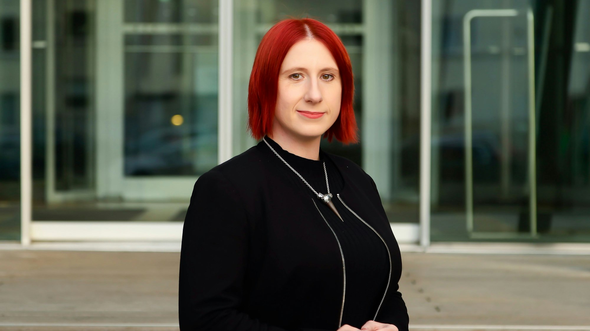 Lydia Benecke trägt ein schwarzes Kleid und eine schwarze Jacke und blickt in die Kamera