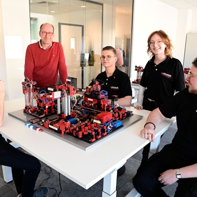 In der Lernwerkstatt der Firma Unitechnik sitzen mehrere Personen an einem Tisch um ein Modell herum.
