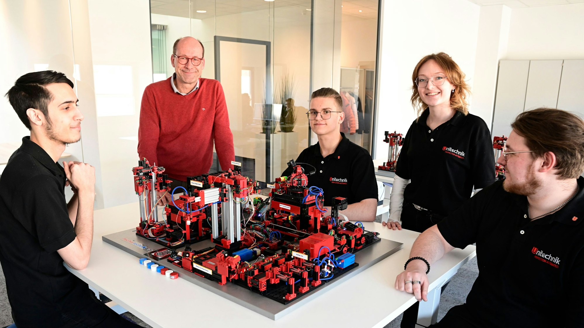 In der Lernwerkstatt der Firma Unitechnik sitzen mehrere Personen an einem Tisch um ein Modell herum.