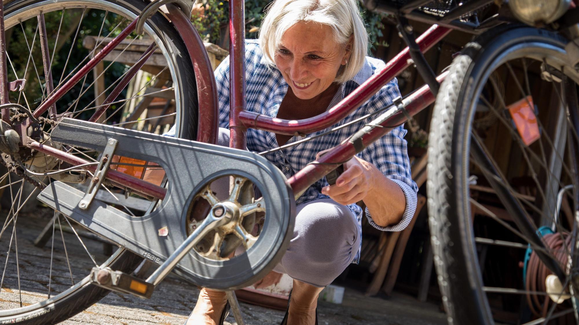Eine Frau ölt die Kette eines Fahrrads.