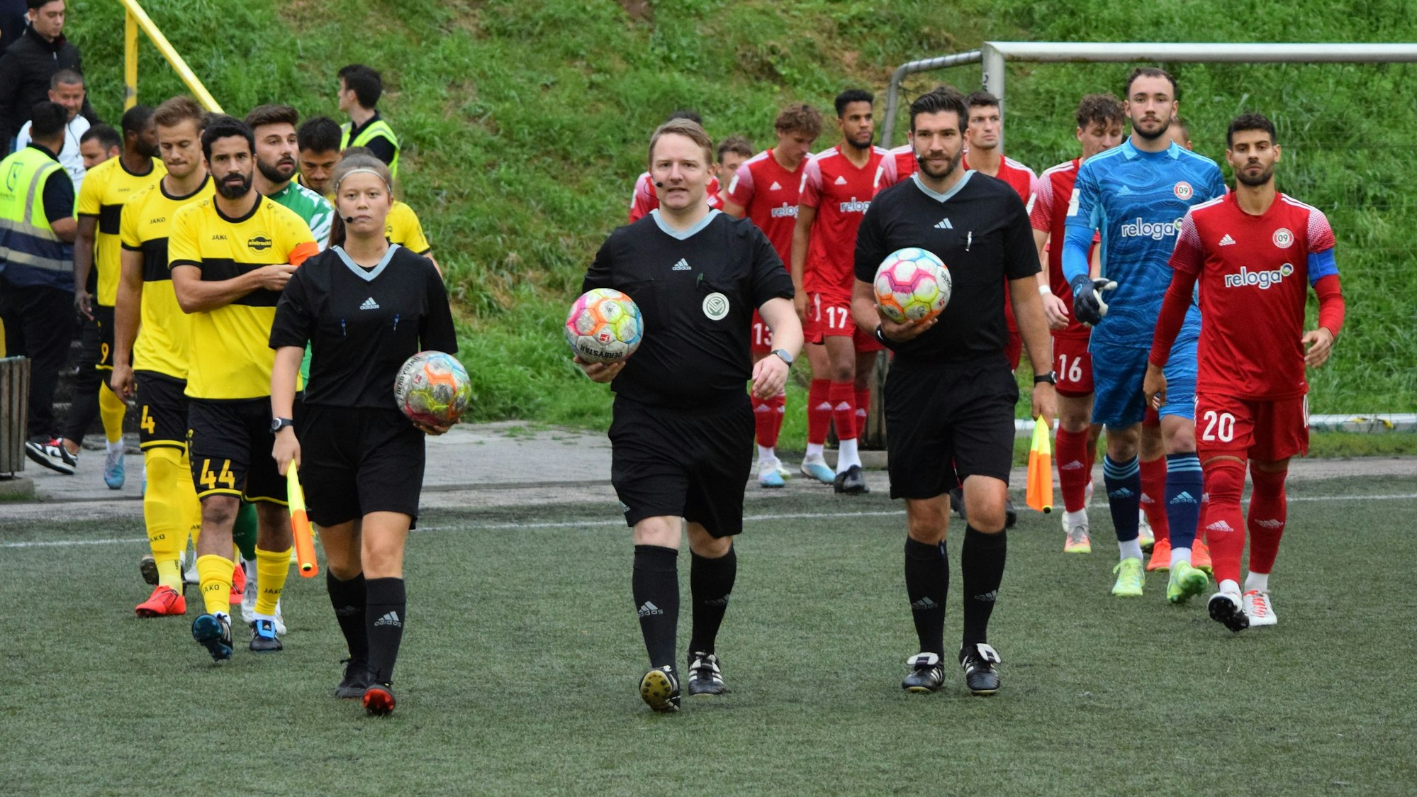 Die Spieler von Eintracht Hohkeppel und dem SV Bergisch Gladbach 09 laufen auf den Fußballplatz.