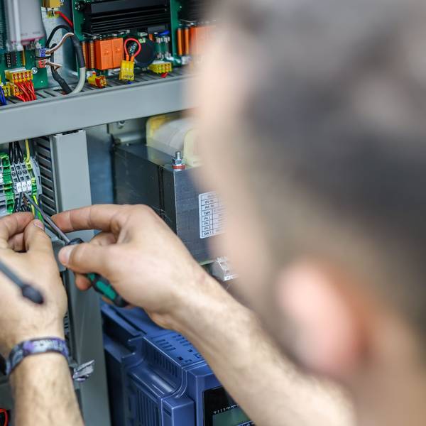 Ein Handwerker verdrahtet die Steuerung einer großen Maschine.