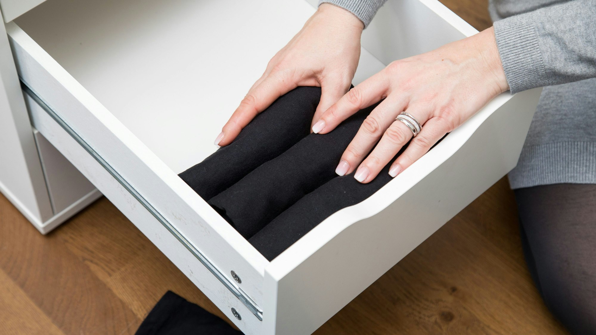 Frauenhände sortieren Kleidungsstücke in einer Schublade.