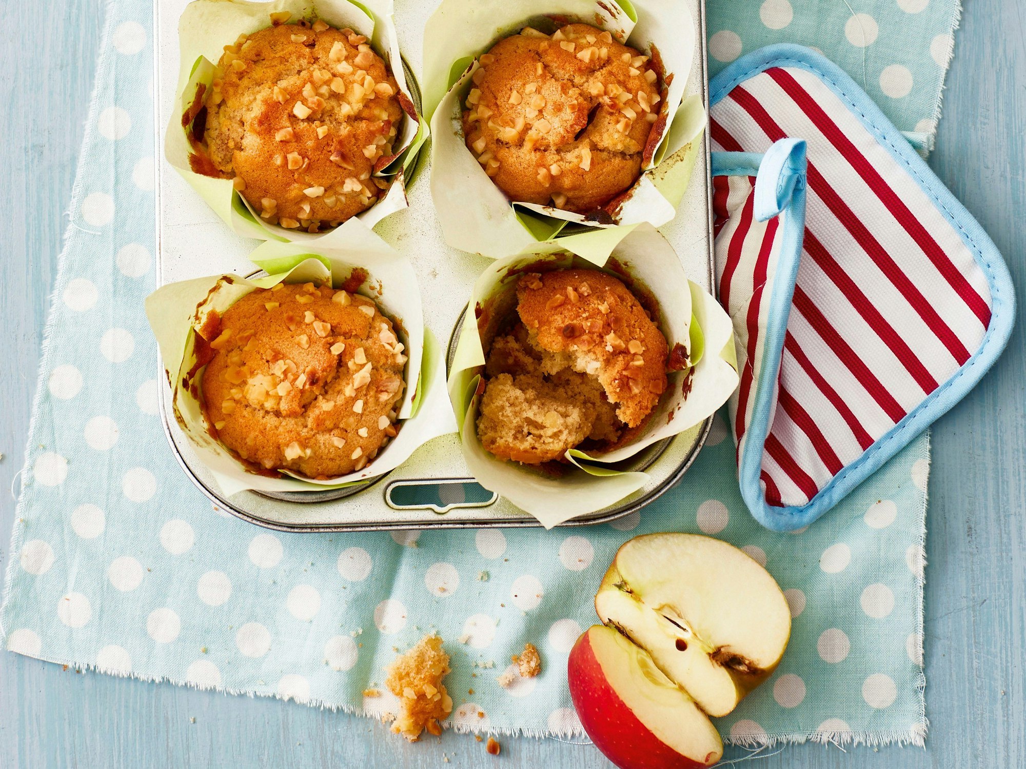 Vier Apfelmuffins liegen fertig gebacken in einer Muffin-Form.