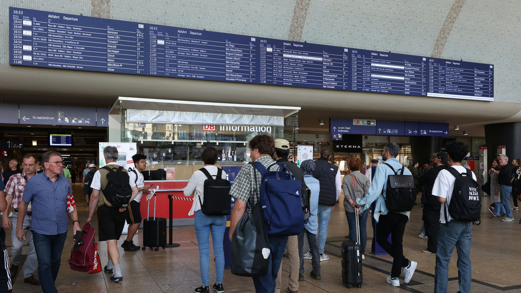 Viele Menschen stehen in der Eingangshalle des Kölner Hauptbahnhofs und schauen auf die große Anzeigetafel.
