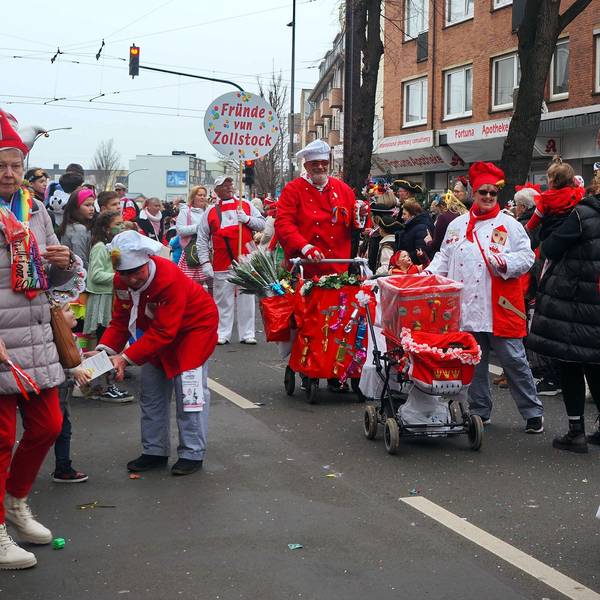 Kostümierte Jecke ziehen über die Straße.
