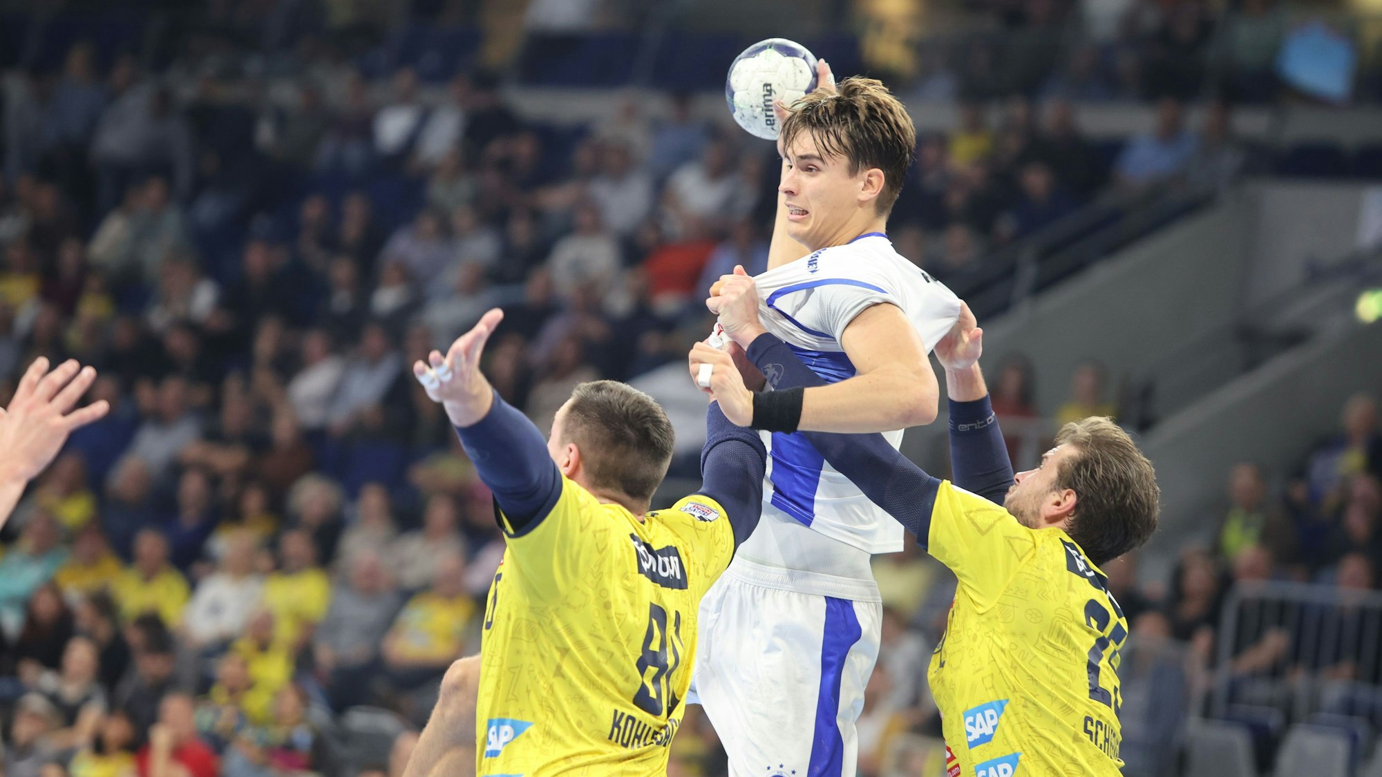 Eine Spielsituation auf dem Handballfeld. VfL-Spieler Julian Köster setzt zum Sprungwurf an, dabei wird er von zwei Abwehrspielern aufgehalten.