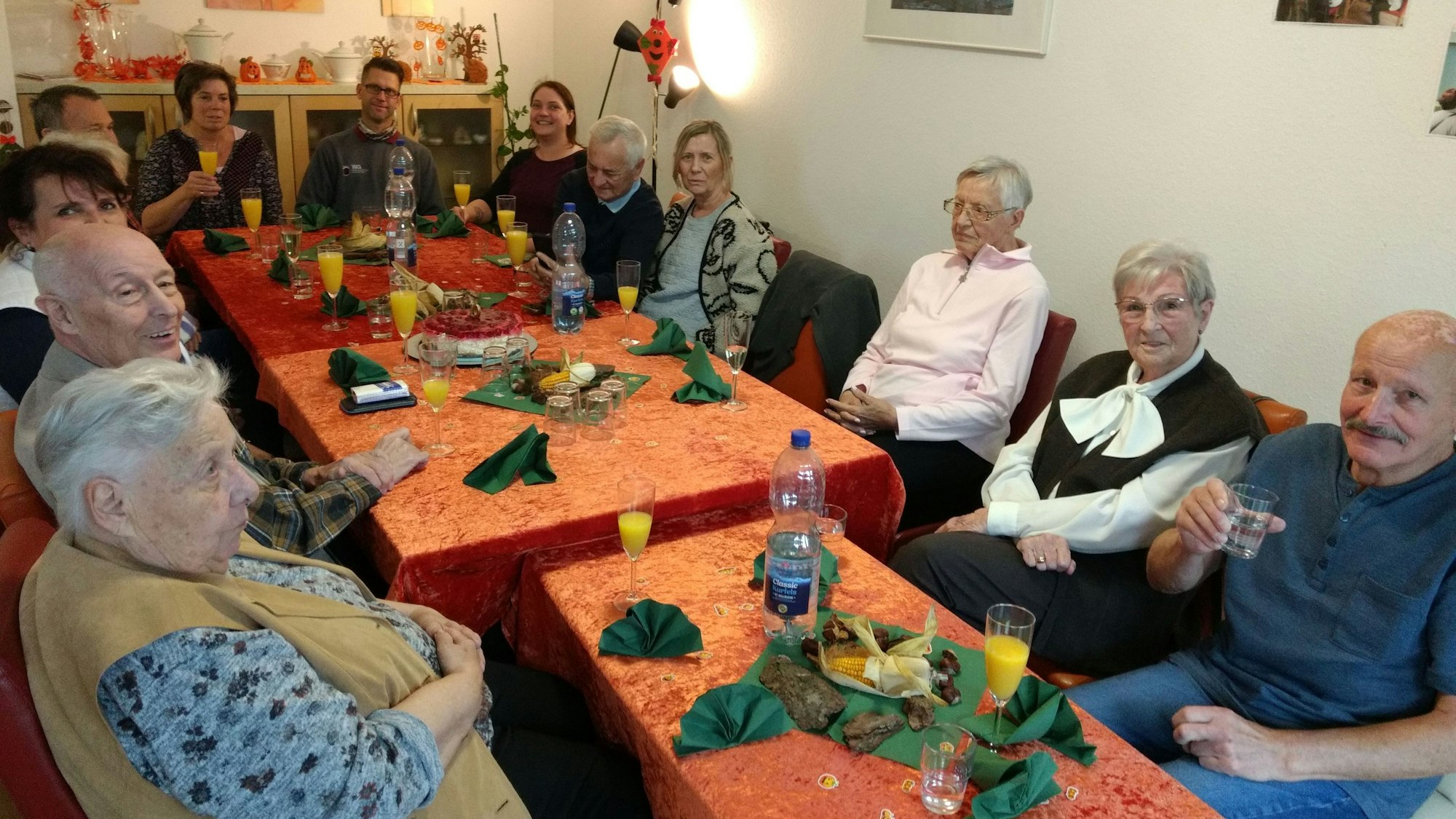 Seniorinnen und Senioren sitzen an einem Tisch und prosten sich zu.