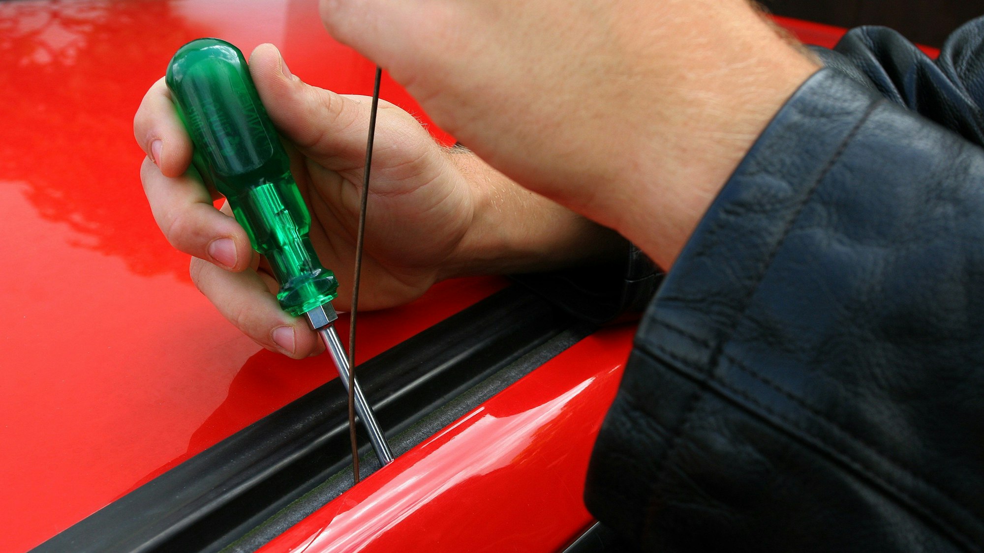 Eine Autotür wird mit Hilfe eines Schraubenziehers geöffnet.