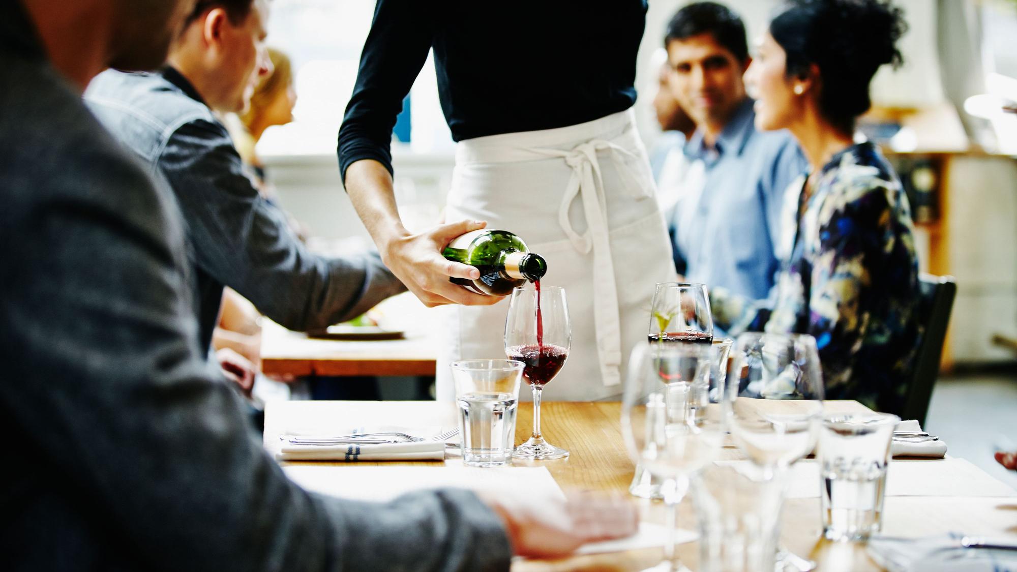 Kellnerin schüttet Wein in ein Glas in einem Restaurant Foto: Getty Images/Thomas Barwick