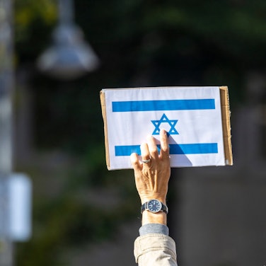 Ein Teilnehmer der Kundgebung «Aufstehen gegen Israelhass und Antisemitismus» hält ein Schild mit der israelischen Flagge in die Höhe.