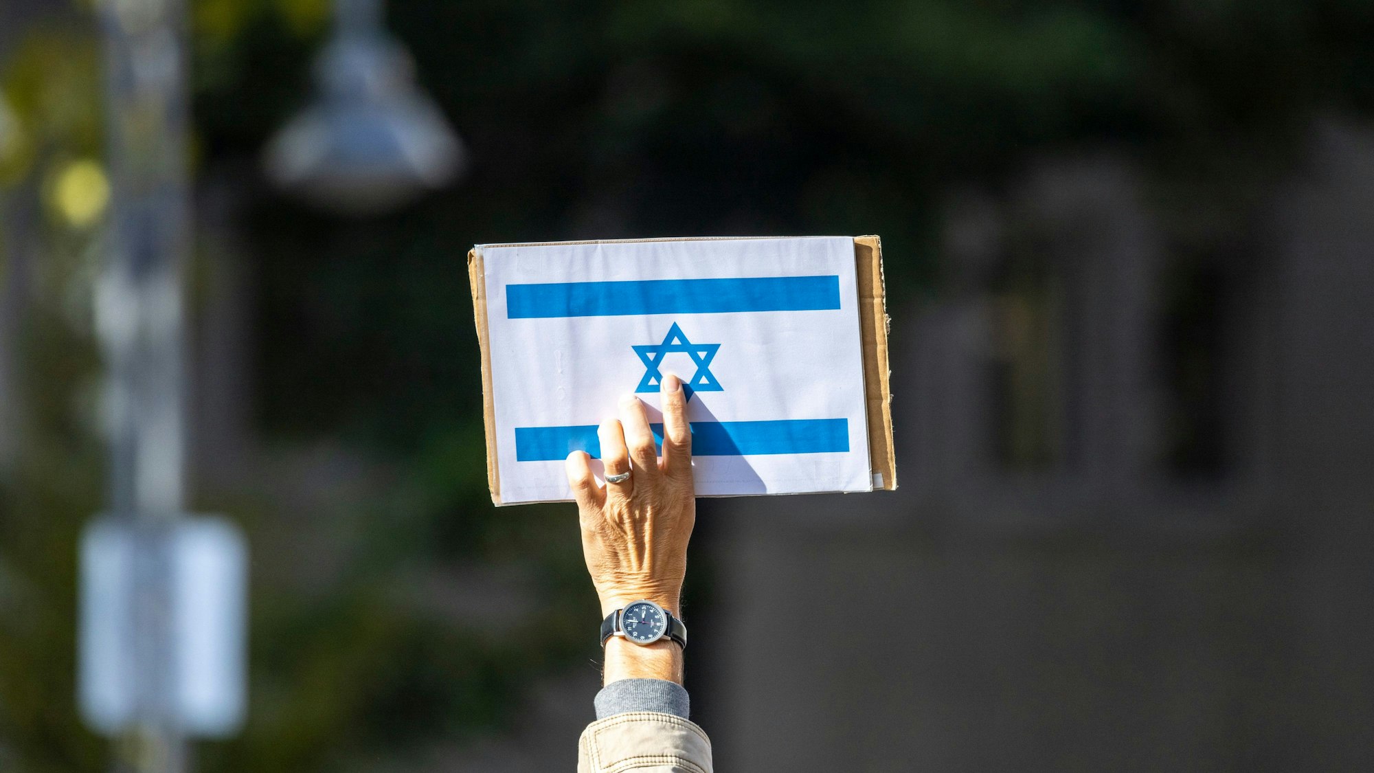 Ein Teilnehmer der Kundgebung «Aufstehen gegen Israelhass und Antisemitismus» hält ein Schild mit der israelischen Flagge in die Höhe.