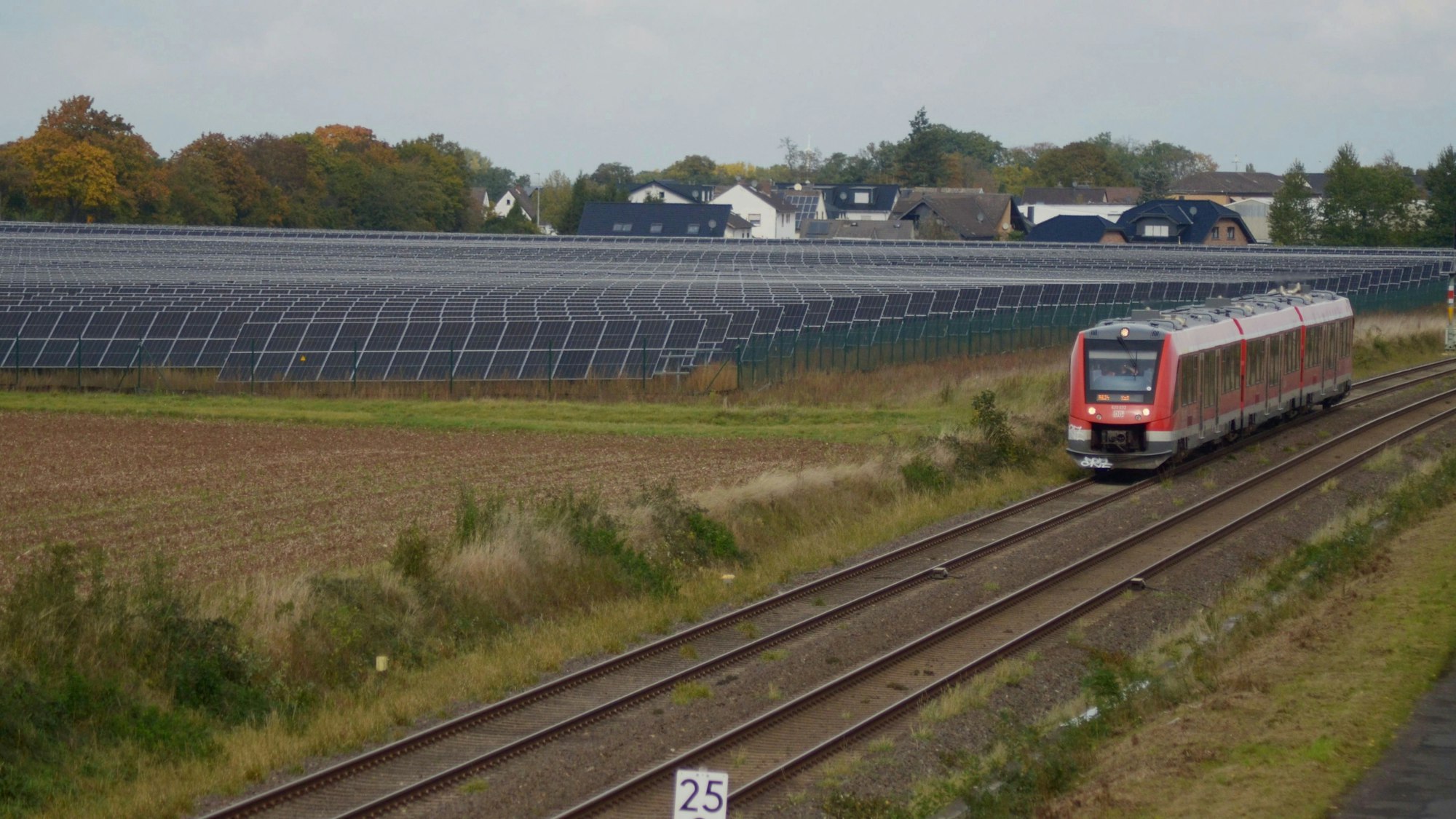 Ein Solarpark in der Nähe der Ortschaft Ottenheim. Er liegt neben einer Bahnstrecke, auf der gerade ein Zug unterwegs ist.