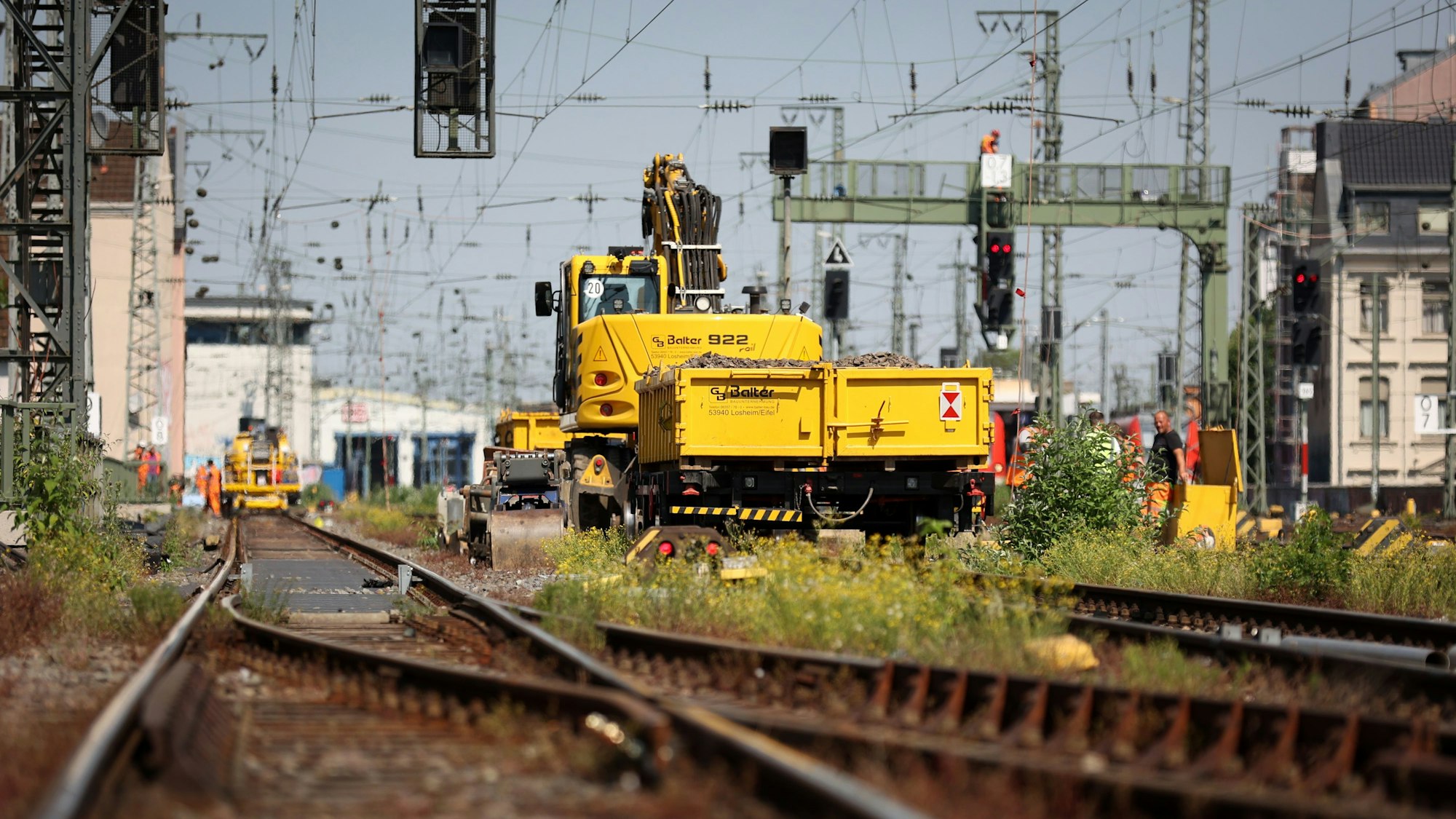 Ein großes, gelbes Baufahrzeug ist auf den Gleisen nahe dem Kölner Hauptbahnhof bei Umrüstungsarbeiten für Fern- und Regionalverkehr zu sehen.