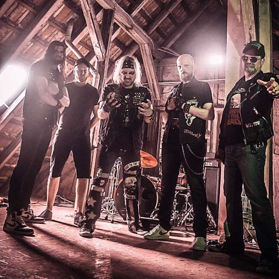 Fünf Musiker posieren auf einem alten Dachboden.