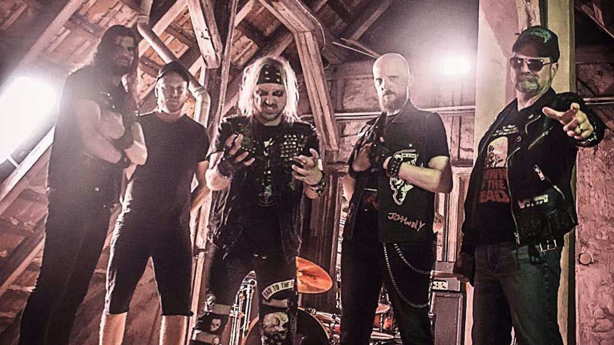 Fünf Musiker posieren auf einem alten Dachboden.