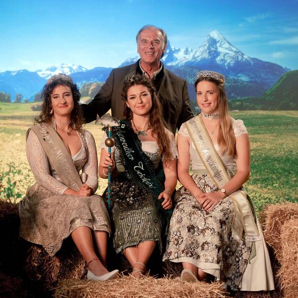 Die Königinnen sitzen, hinter ihnen thront Josef Gehrling als ihr Patriarch. Rechts und links neben ihnen Stroh und ein Milchkübel, im Hintergrund eine bayrische Landschaft. Das Bild ist bewusst überzeichnet und spielt mit bayrischen Klischees.