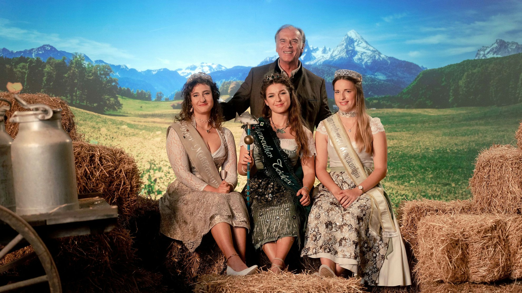 Die Königinnen sitzen, hinter ihnen thront Josef Gehrling als ihr Patriarch. Rechts und links neben ihnen Stroh und ein Milchkübel, im Hintergrund eine bayrische Landschaft. Das Bild ist bewusst überzeichnet und spielt mit bayrischen Klischees.