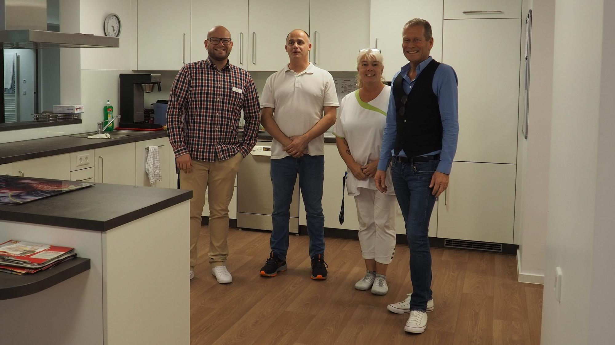 Vier Personen stehen in einer neuen Küche.