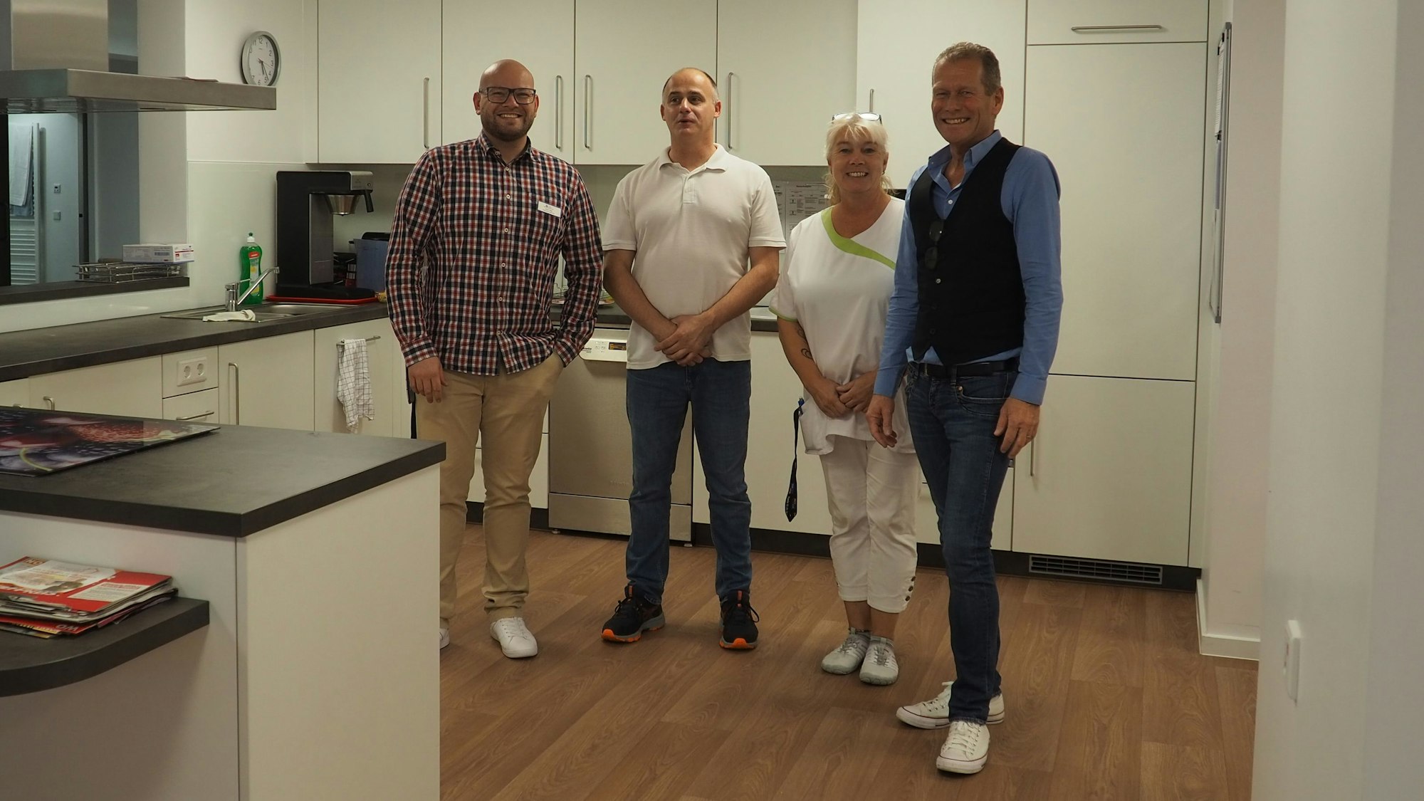 Vier Personen stehen in einer neuen Küche.