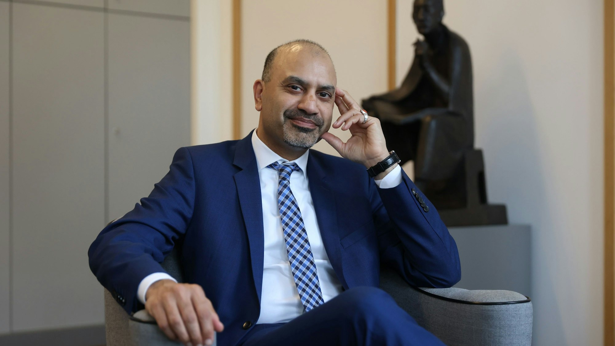 Der neue Uni-Rektor Joybrato Mukherjee
im Rektoratsbüro. Im Hintergrund ist eine Statur von Albertus Magnus zu sehen, dem Namenspatron der Uni Köln.