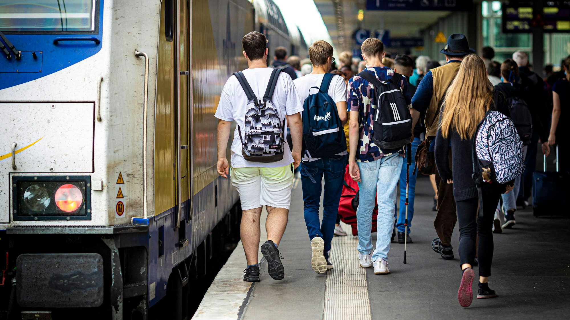 Reisende gehen einen Bahnsteig entlang.