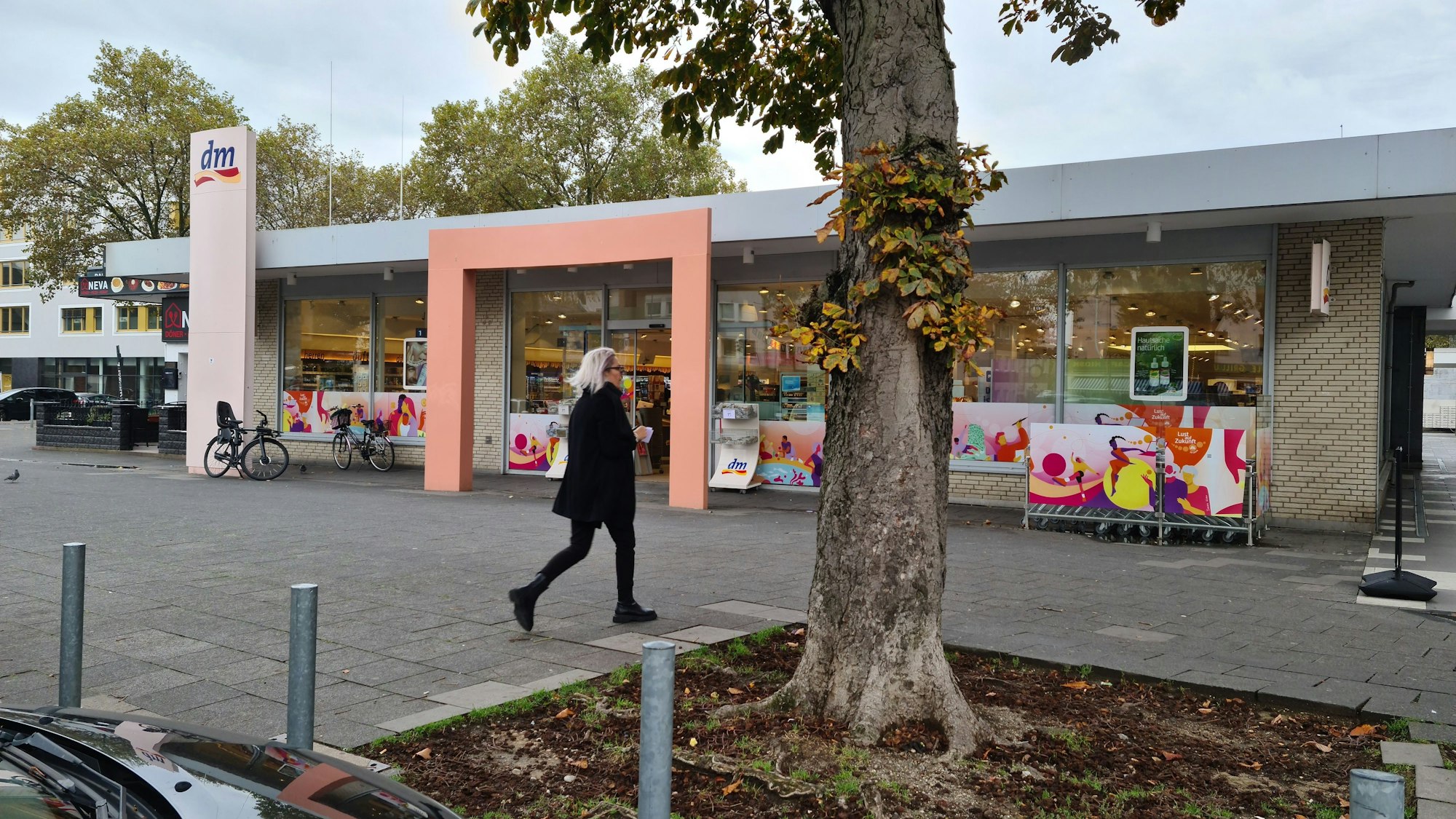 In einem Flachbau ist ein Drogeriemarkt untergebracht. Im Vordergrund steht ein Baum.