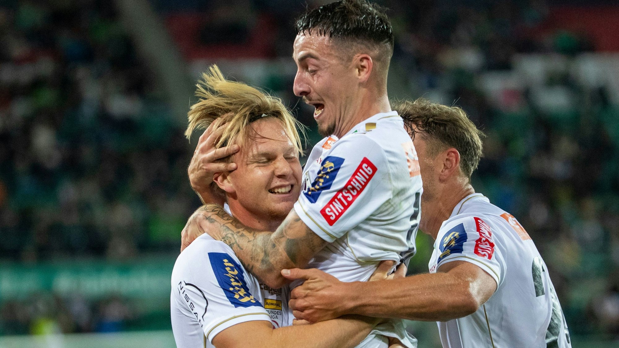 Drei Fußballer bejubeln ein Tor.