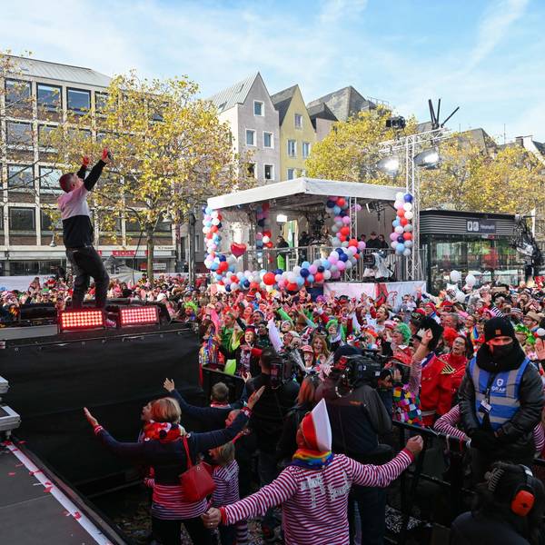 Kasalla stehen auf der Bühne auf dem Heumarkt, vor ihnen feiern Tausende Jecken.