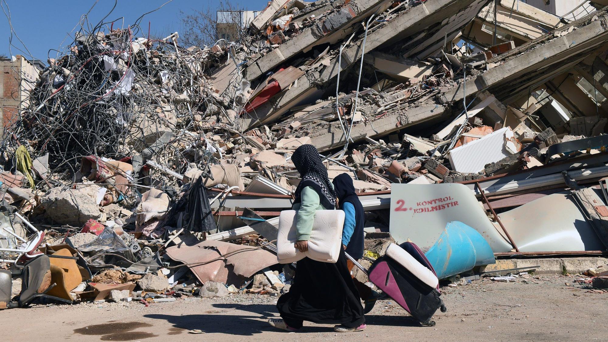 Mitte Februar 2023 in Adiyaman: Menschen gehen an einem eingestürzten Gebäude vorbei.