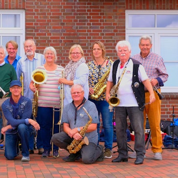 Die 14 Musiker posieren mit ihren Instrumenten