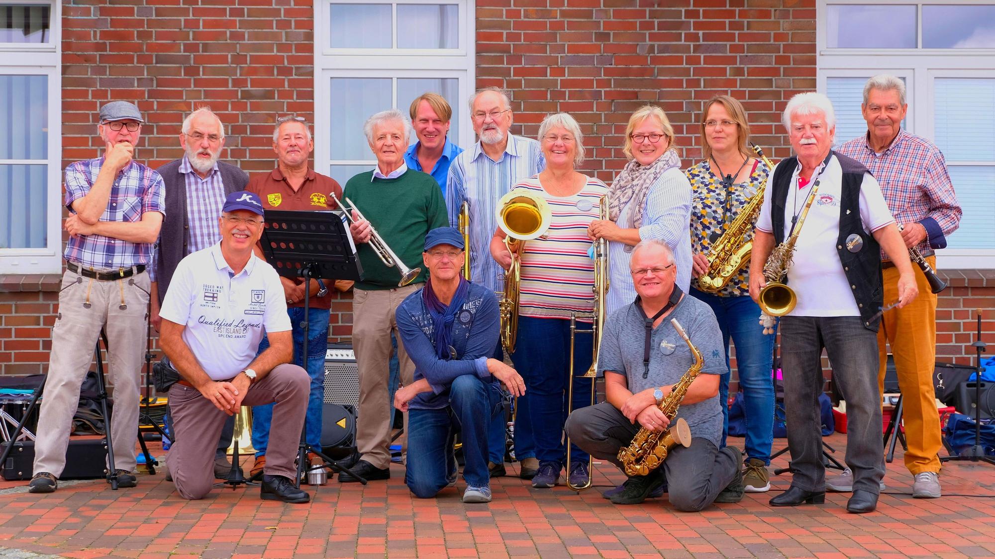 Die 14 Musiker posieren mit ihren Instrumenten