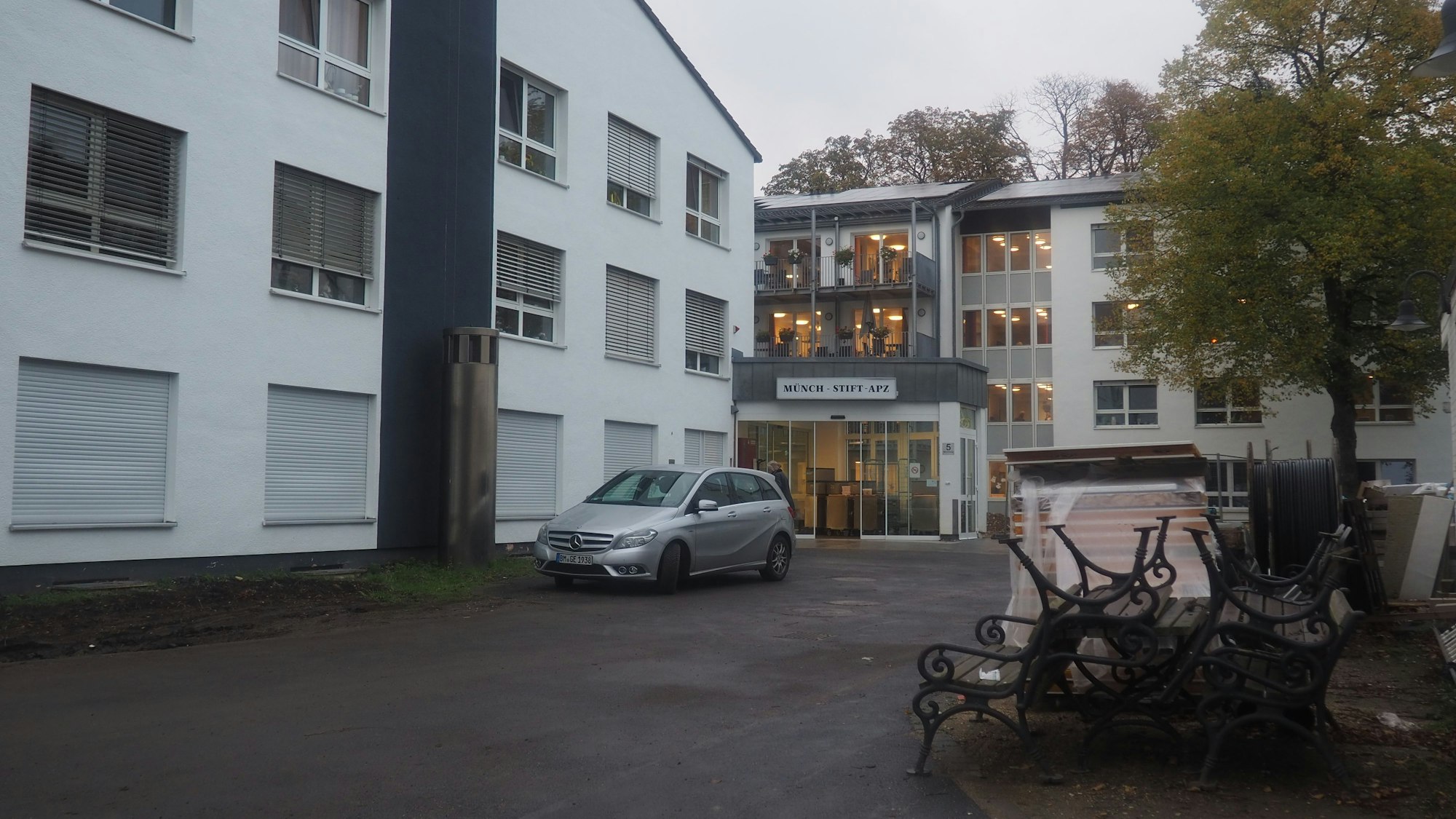 Vor dem sanierten Gebäude sind Bänke und andere Dinge gestapelt.