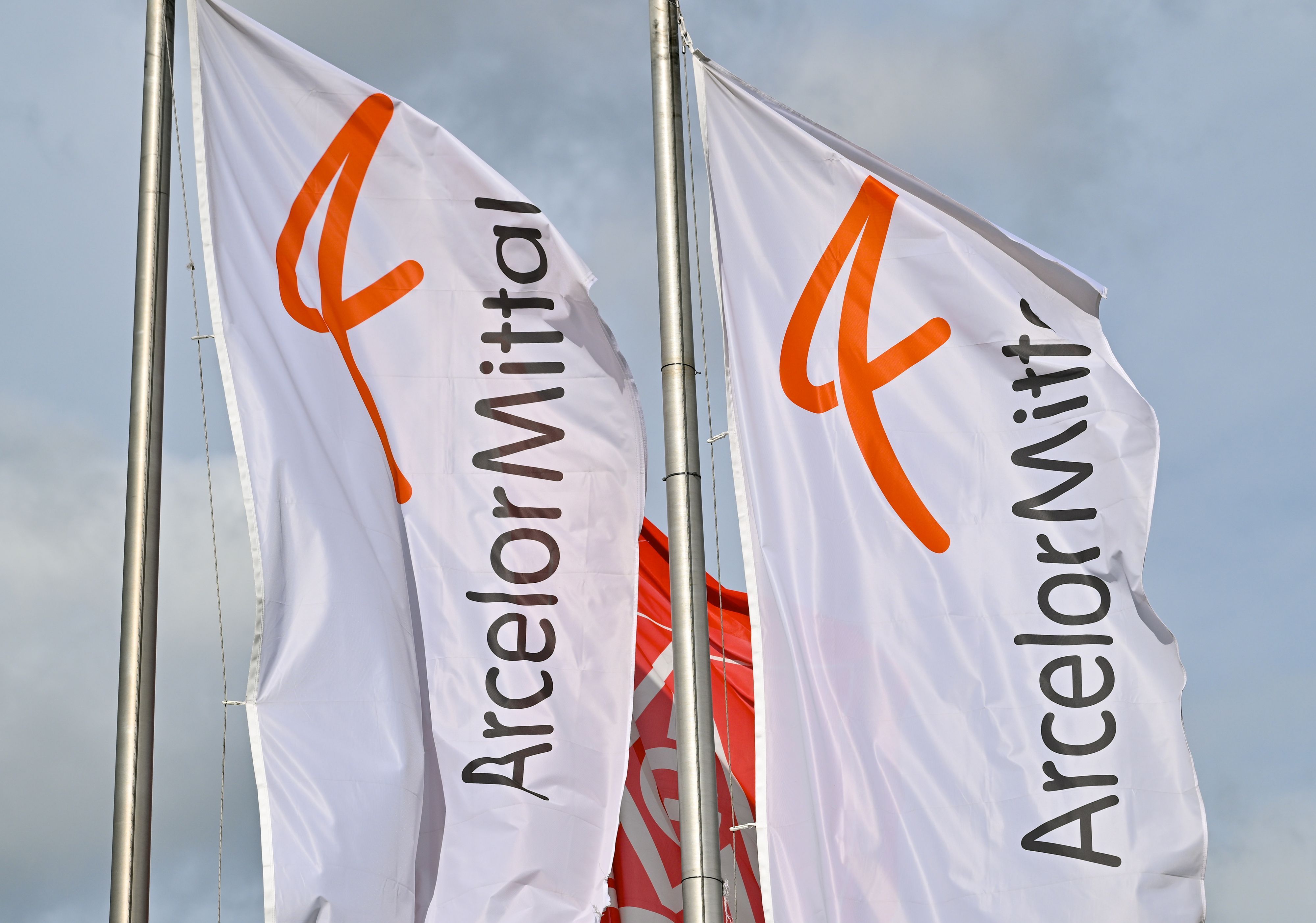ARCHIV - 14.03.2023, Brandenburg, Eisenhüttenstadt: Fahnen vom Stahlproduzenten ArcelorMittal wehen im Wind. (zu dpa «Für klimaneutrale Stahlproduktion: Aufbau von Wasserstofferzeugung») Foto: Patrick Pleul/dpa +++ dpa-Bildfunk +++