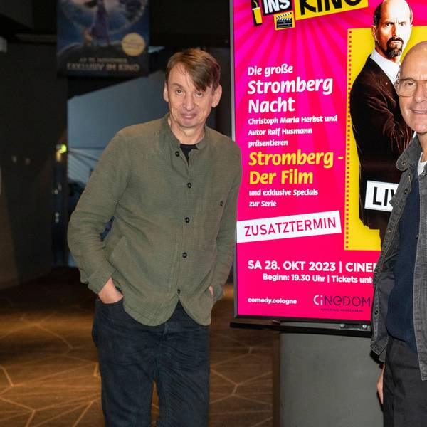 Christoph Maria Herbst und Ralf Husmann posieren neben einem digitalen Poster von Stromberg im Cinedom.