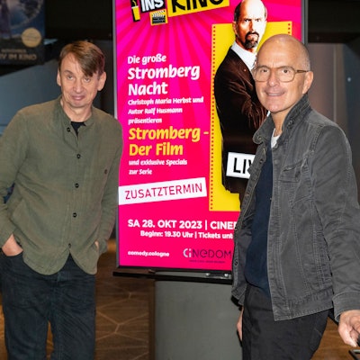 Christoph Maria Herbst und Ralf Husmann posieren neben einem digitalen Poster von Stromberg im Cinedom.