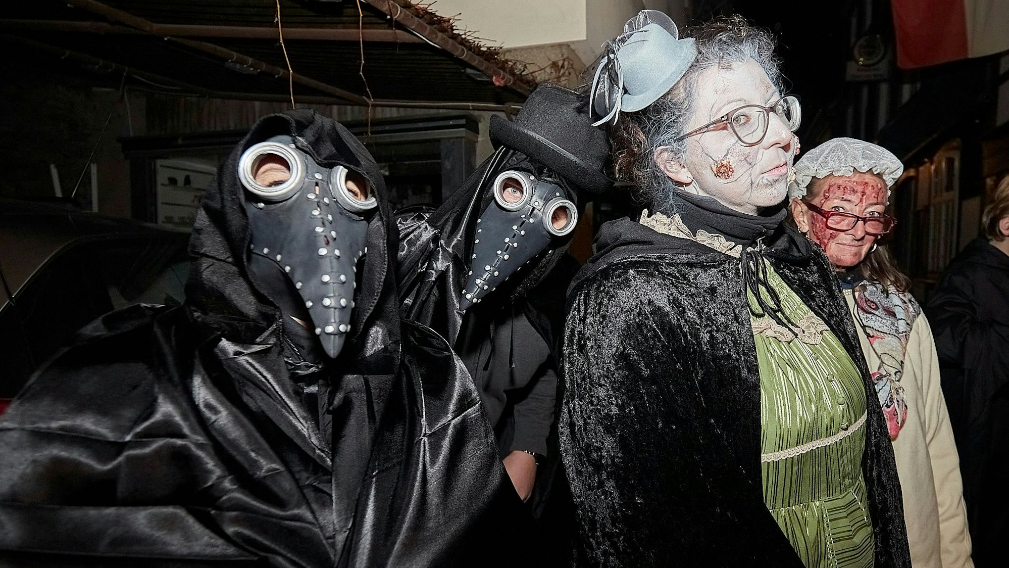 Zu sehen sind zwei Personen mit Masken und zwei Frauen, die als Pestkranke geschminkt sind.