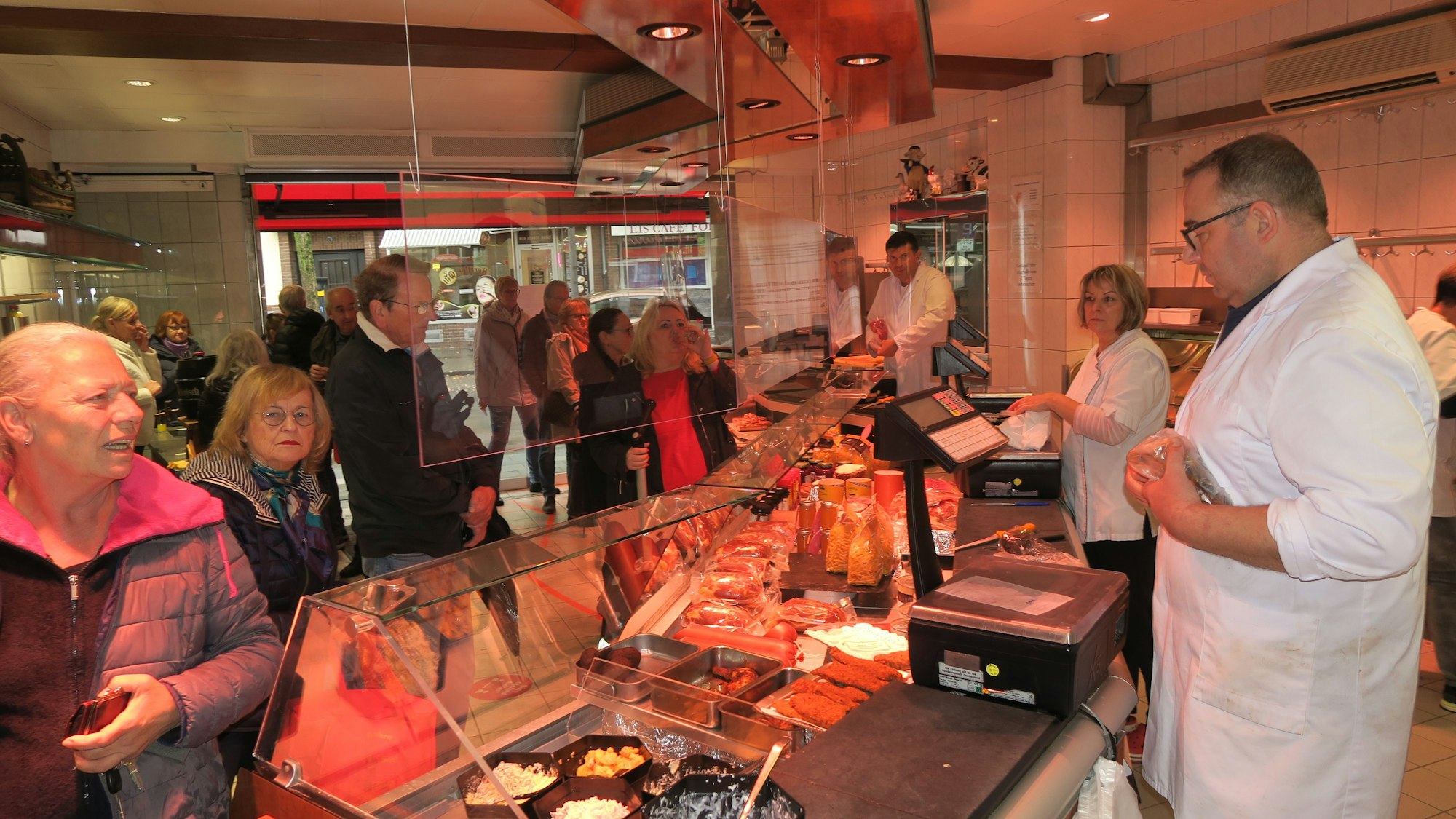 In einer Metzgerei stehen viele Kunden vor der Verkaufstheke.