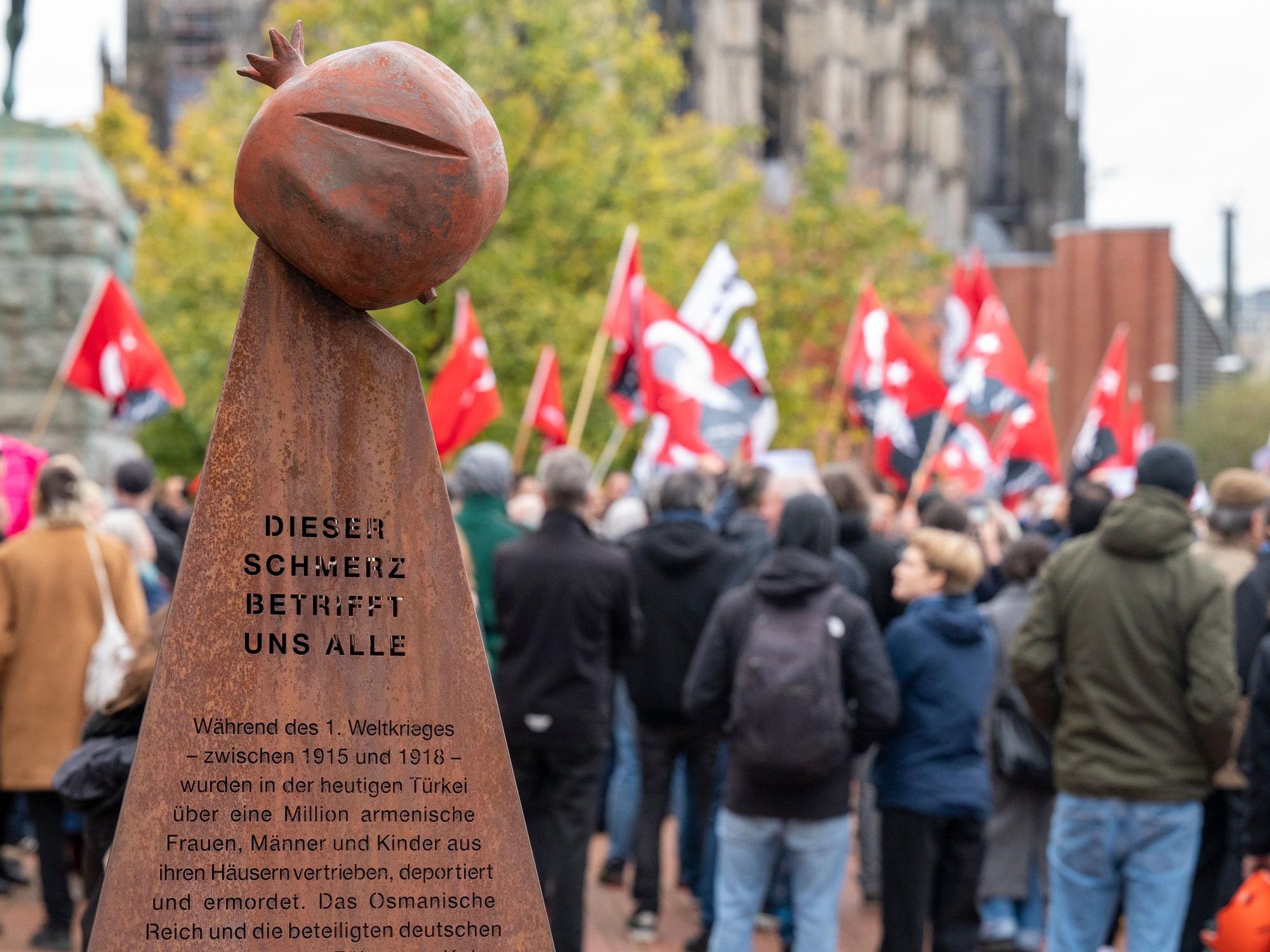 Im Vordergrund ist das Mahnmal zu sehen, das an den Völkermord an den Armeniern erinnert. Im Hintergrund sind Demonstranten zu sehen.
