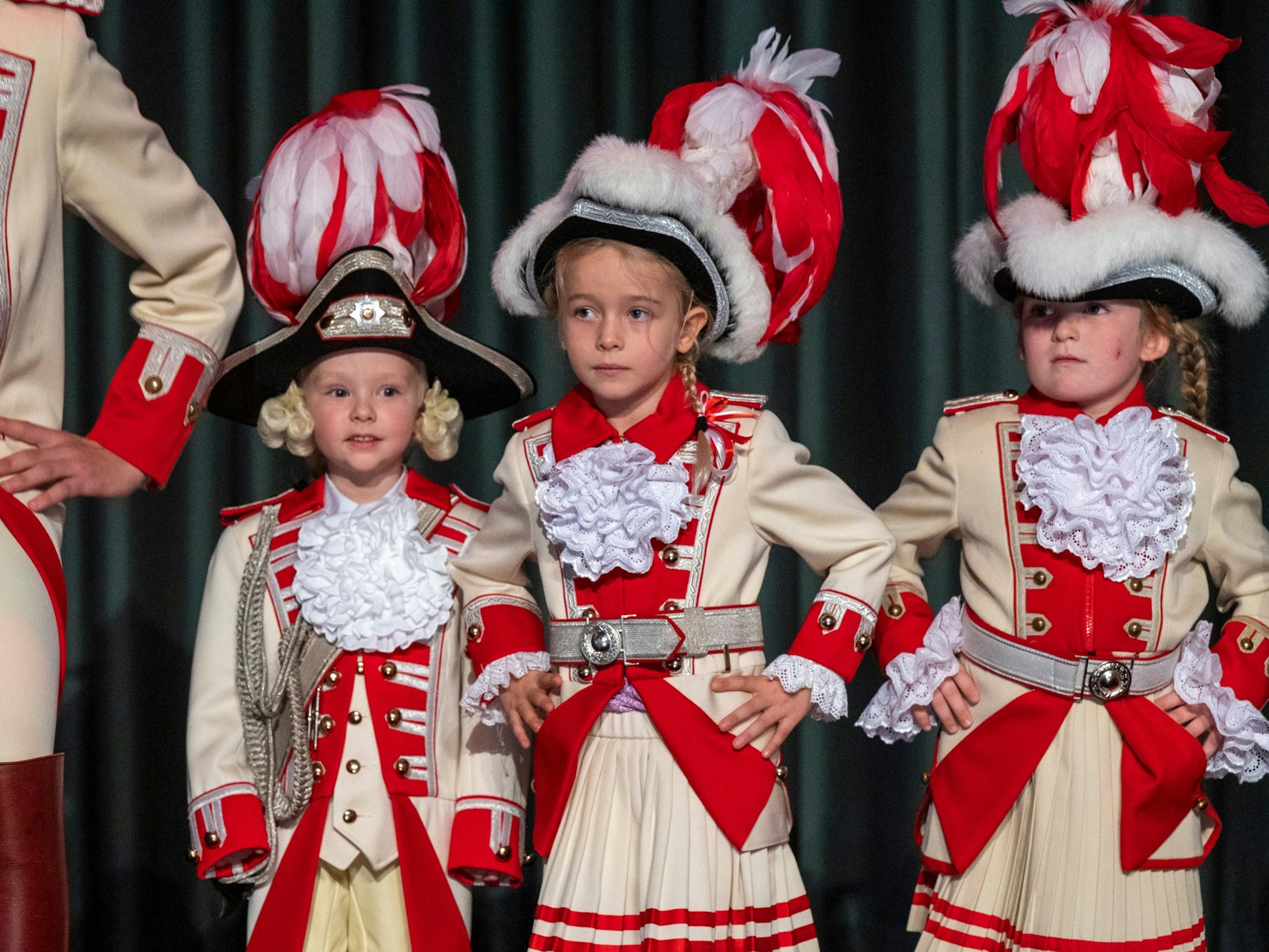 Kinder einer Tanzgruppe stehen in ihren Uniformen auf einer Bühne.