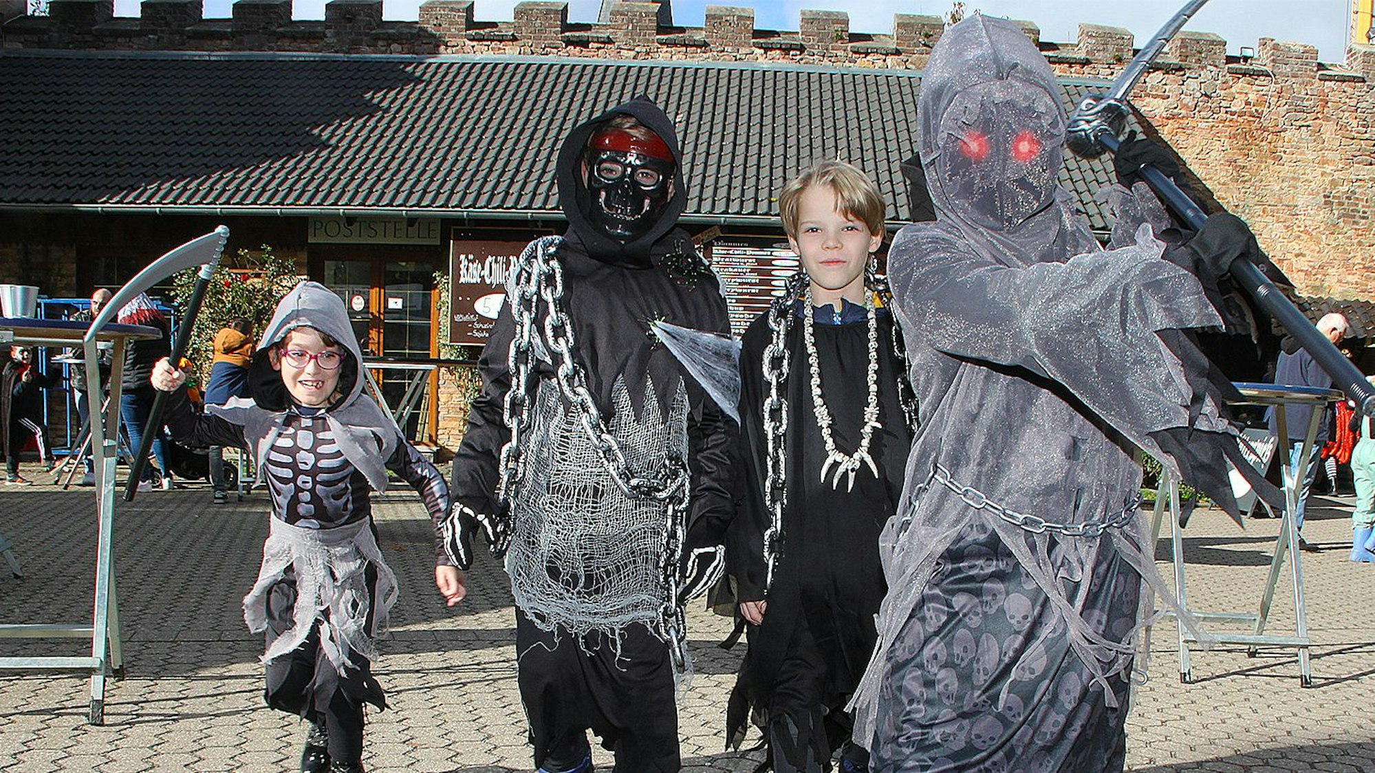 Die vier Kinder haben sich aus Raubritter kostümiert und mit Ketten behangen. Der Kleinste schwingt eine Sense.