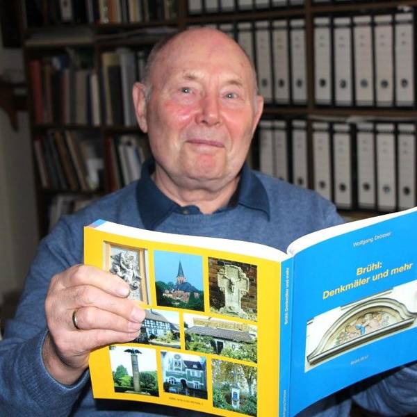 Zu sehen ist Wolfgang Drösser, der eines der selbst verfassten Bücher in den Händen hält.